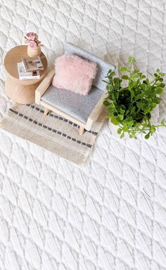 a chair with a pink pillow on top of it next to a potted plant