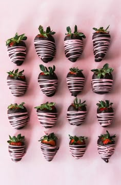 chocolate covered strawberries are arranged on a pink surface