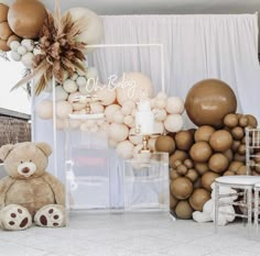 a teddy bear sitting in front of some balloons and other decorations on the wall behind it