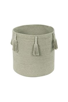 a large round basket with tassels on the sides and handles, in light green