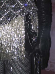 a woman's black and silver dress with sequins on the skirt, along with gloves