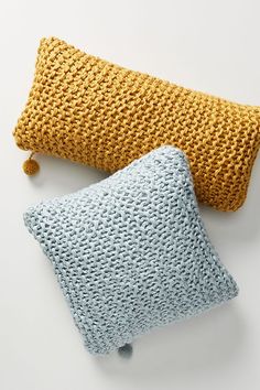 two knitted pillows sitting next to each other