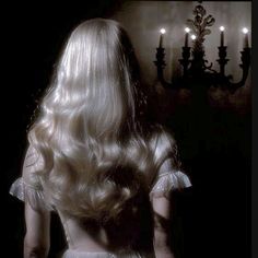 the back of a woman's head in front of a wall with candles on it