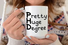 a woman holding a white coffee mug with the words pretty huge degree on it's side