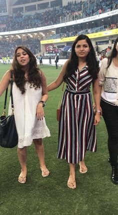 two women holding hands while standing on a field