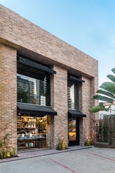 the outside of a brick building with many windows and plants on the sidewalk in front of it