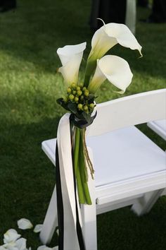 a bouquet of flowers sitting on top of a white bench in the grass with people standing behind it