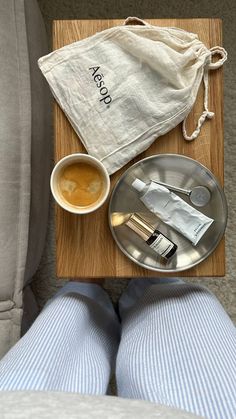 a tray with a cup and saucer on it next to a person's legs