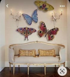 a white couch sitting in front of a wall mounted butterflies