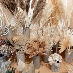 several vases filled with dried plants on a table