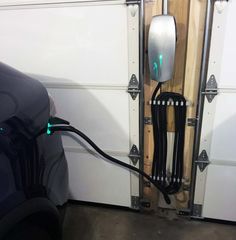 an electric vehicle plugged in to a wall with wood and metal brackets on it