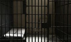 a bed in a jail cell with bars on it