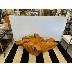 a large wooden sculpture sitting on top of a black and white striped floor next to a table