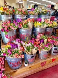 several buckets filled with colorful flowers sitting on top of a wooden table in a store