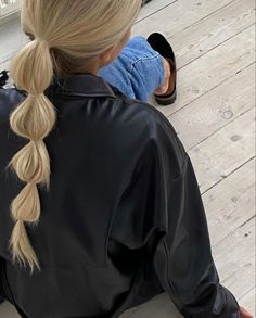 a woman sitting on the ground with her hair in a fishtail braid