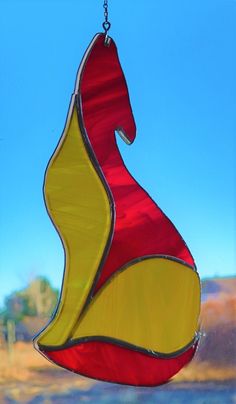 a red and yellow wind chime hanging from a chain on a blue sky background