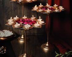 three tiered trays with candles and flowers on them