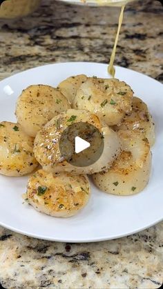 some food is being drizzled with sauce on a white plate and sitting on a marble counter top