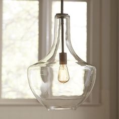 a clear glass light fixture hanging from a ceiling in a room with white walls and windows