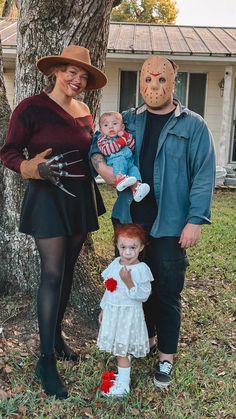 two adults and a child dressed up in halloween costumes, standing next to a tree