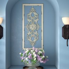 a vase filled with flowers sitting on top of a blue shelf next to a mirror