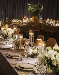 a long table is set with white flowers, candles and place settings for an event