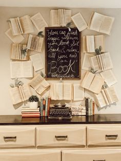 an old typewriter is surrounded by books and other writing implements on a dresser in front of a chalkboard that says you can read