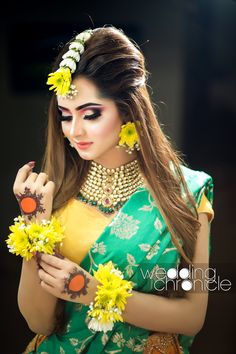 a woman with flowers in her hair is holding some yellow and white flowers on her head