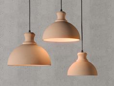 three light fixtures hanging from the ceiling in a room with concrete walls and flooring