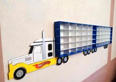 a toy truck is mounted to the side of a wall with shelves on each side