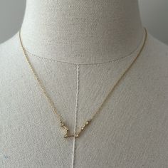 a gold necklace on a mannequin neck with an arrow and star charm hanging from it