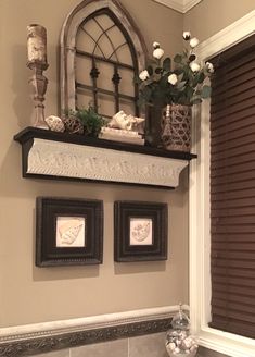 a bathroom with two framed pictures on the wall and flowers in vases next to it