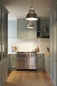 a kitchen with stainless steel appliances and wood flooring is pictured in this image, the light fixture hangs over the stove