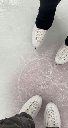 two people in white shoes standing on an ice rink