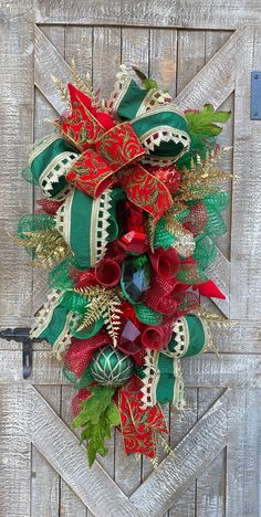 a christmas wreath hanging on the side of a wooden door decorated with bells and ribbons