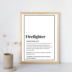 a black and white firefighter definition print in a wooden frame next to a potted plant