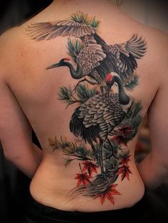 the back of a woman's body is covered in tattoos with birds and leaves