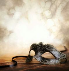 a masquerade mask sitting on top of a wooden table next to a book