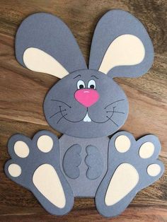 a paper cut out of a rabbit on a wooden surface with the letter b in it's paws