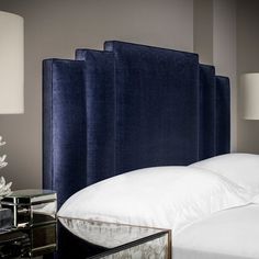 a blue headboard with white sheets and pillows