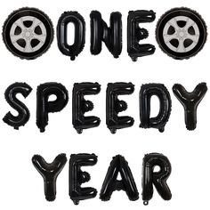 the words one speedy year are made out of black balloon type letters with wheels on them