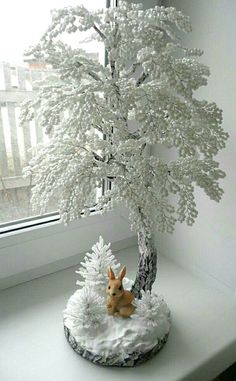 a small white tree sitting on top of a table next to a window sill