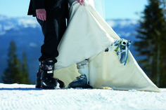 a bride and groom standing next to each other on top of a snow covered slope