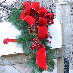 a mailbox decorated with red ribbon and pine cones