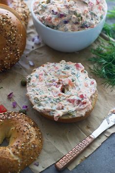 two bagels and a bowl of dip are on the table