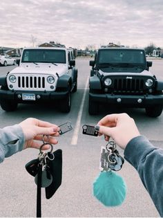 two people handing keys to each other in front of jeeps parked in a parking lot