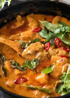 chicken curry with spinach and red peppers in a cast iron skillet, ready to be eaten