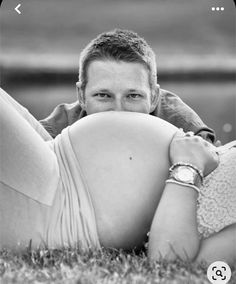 a black and white photo of a man laying in the grass with his hands on his hips