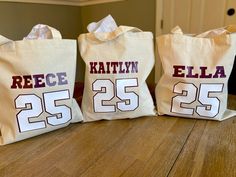 three personalized tote bags sitting on top of a wooden table