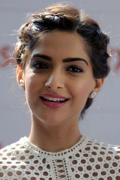 an image of a woman smiling with her hair pulled back and wearing a white dress